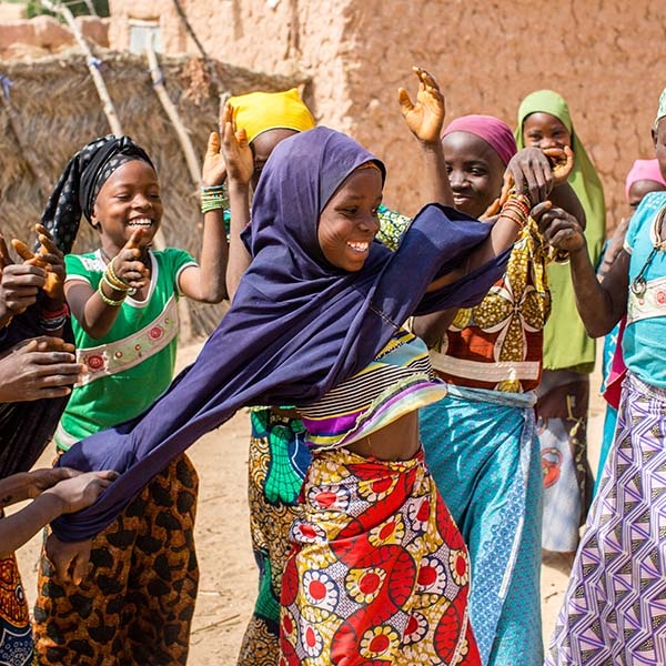 Eleven-year-old Zeinabou (center) smiles and plays with her girlfriends – all in colorful outfits. Eleven-year-old Zeinabou (center) smiles and plays with her girlfriends – all in colorful outfits.